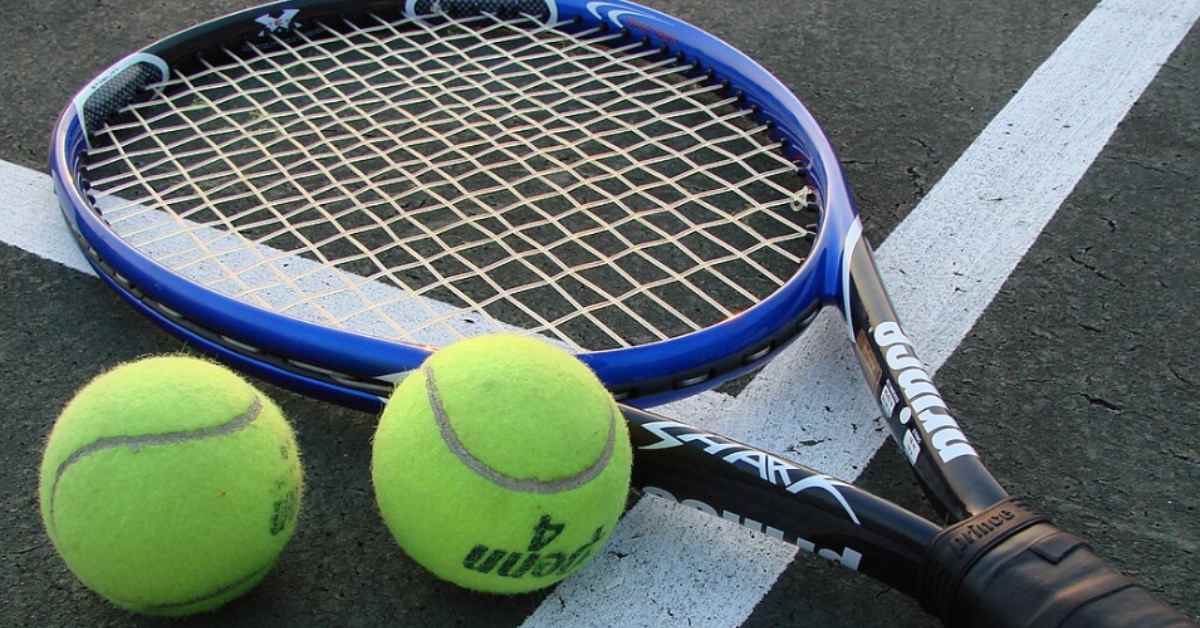 A racquet and two tennis balls on a court