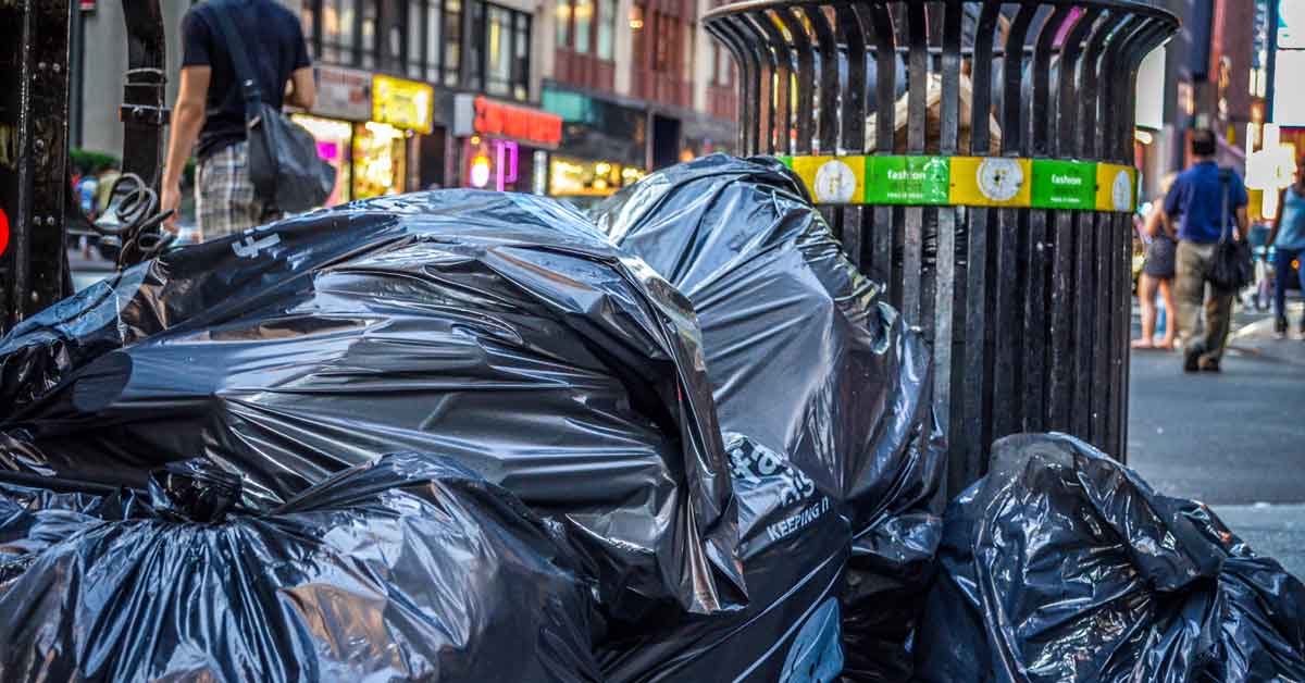 A pile of black trash bags sit on a street in New York