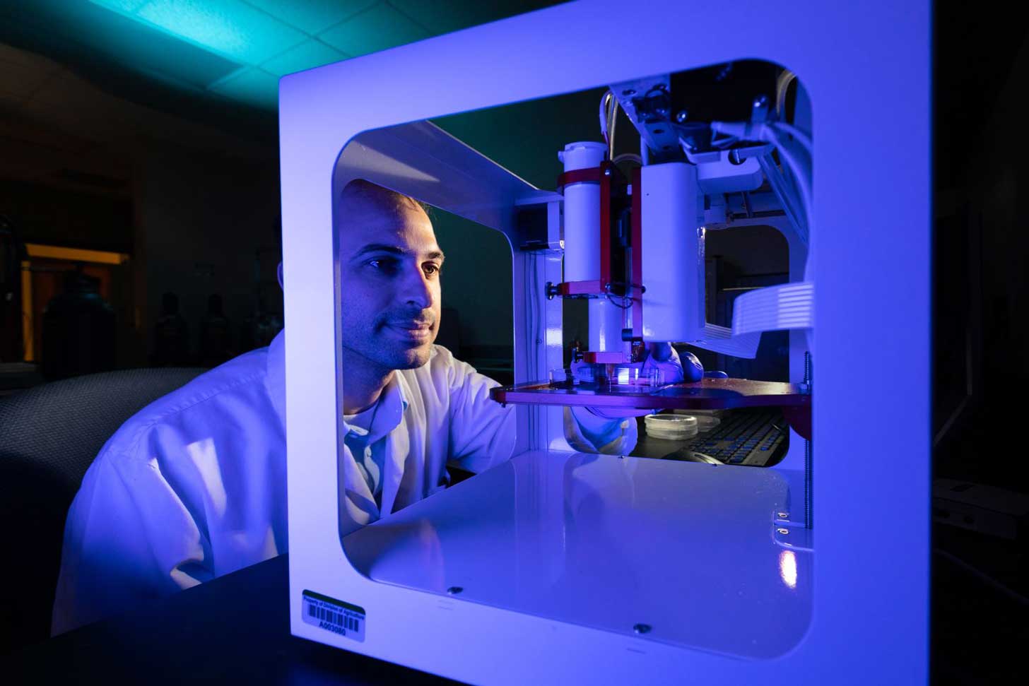A scientist at the University of Arkansas sits in front of a 3D printer