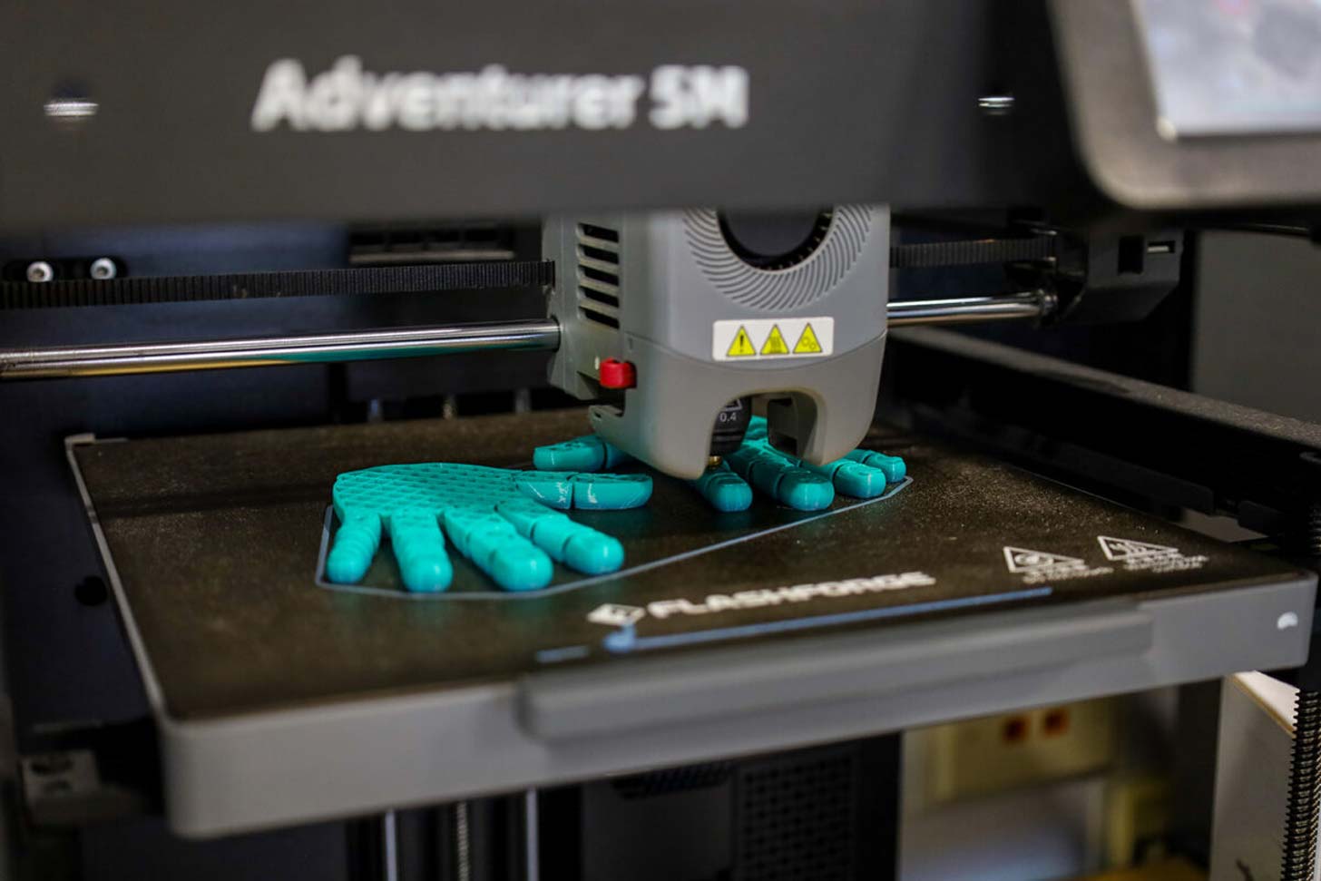 A blue hand is 3D printed in a school lab