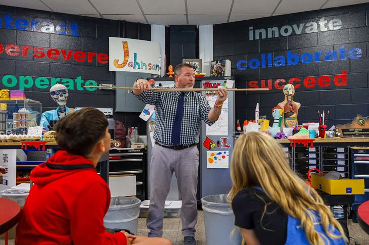 A teacher stands in front of a room of elementary schoolers