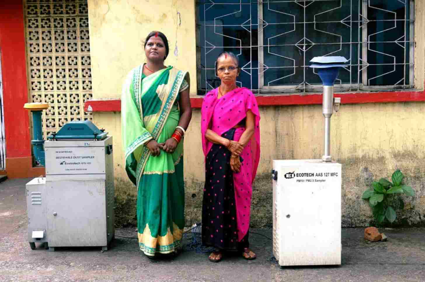 Two women standing next to air pollution detection machines
