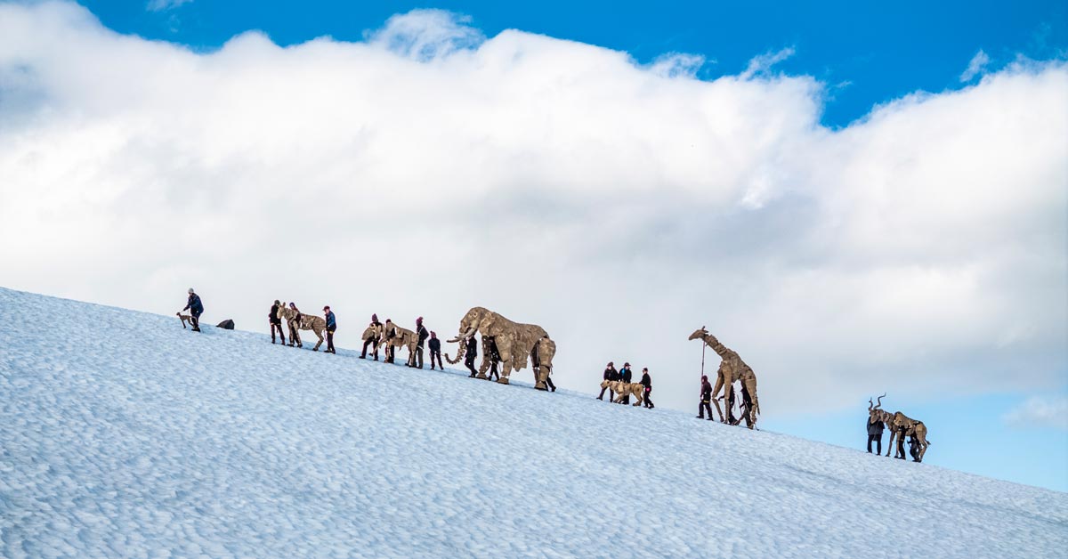 A herd of giant cardboard animal puppets scale a glacier in Jostedalsbreen National Park, Norway