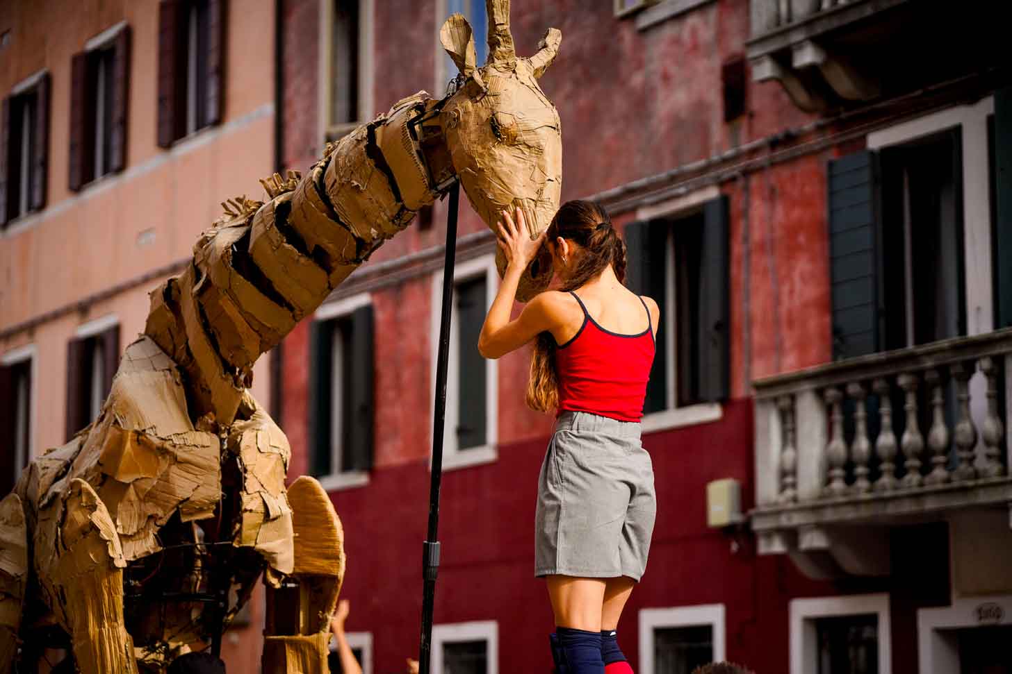 A young woman is face-to-face with a life-size giraffe puppet in Venice, Italy