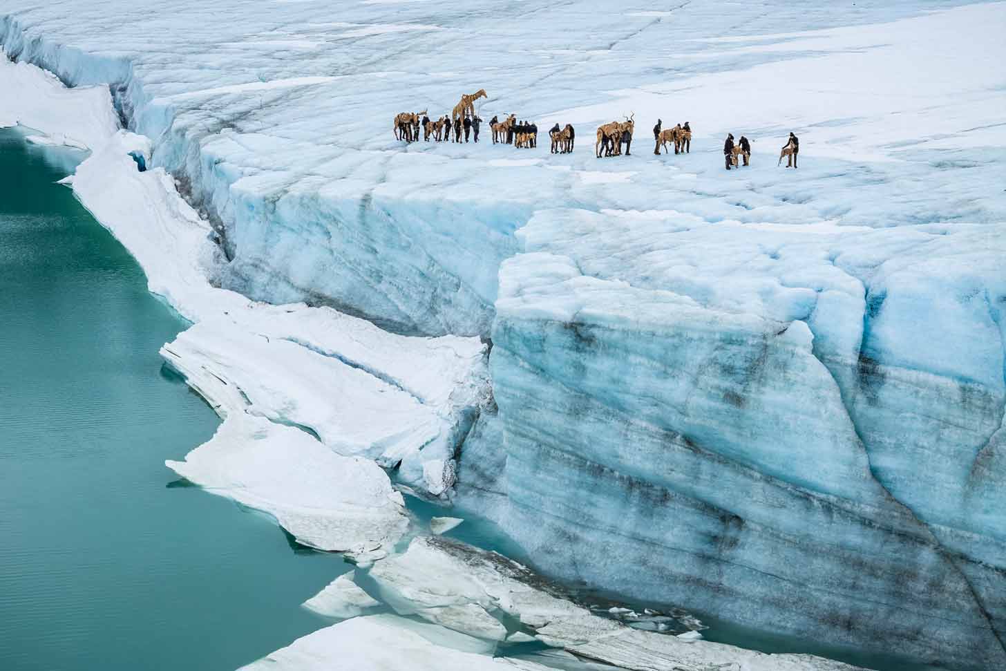 A group of cardboard puppets stand on the edge of a glacier in Norway