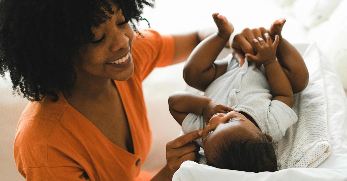 A mother smiling at and holding her baby