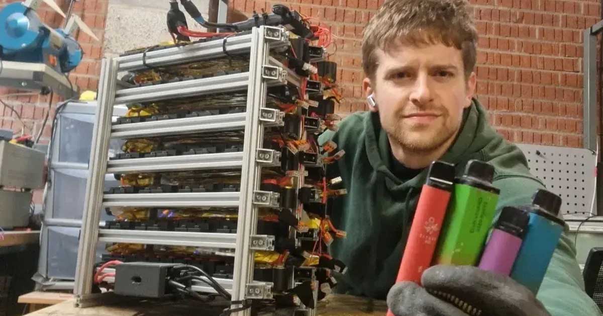 A man, Chris Doel, takes a selfie, holding up a few discarded vapes and sitting next to a large battery cell