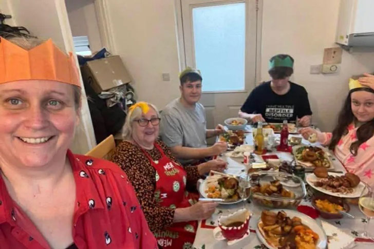 A woman takes a selfie with her family around a holiday dinner table