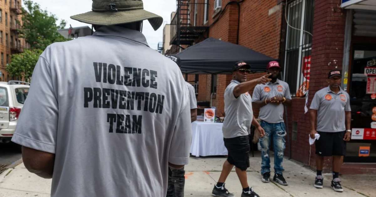 A man wearing a shirt that says 'Violence Prevention Team' as he looks at his team members in the distance