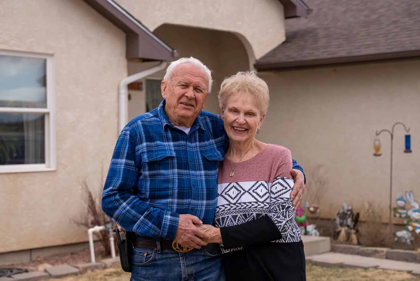 A retired couple, Stan and Cora Krol, hug in front of their home in Pueblo, Colorado