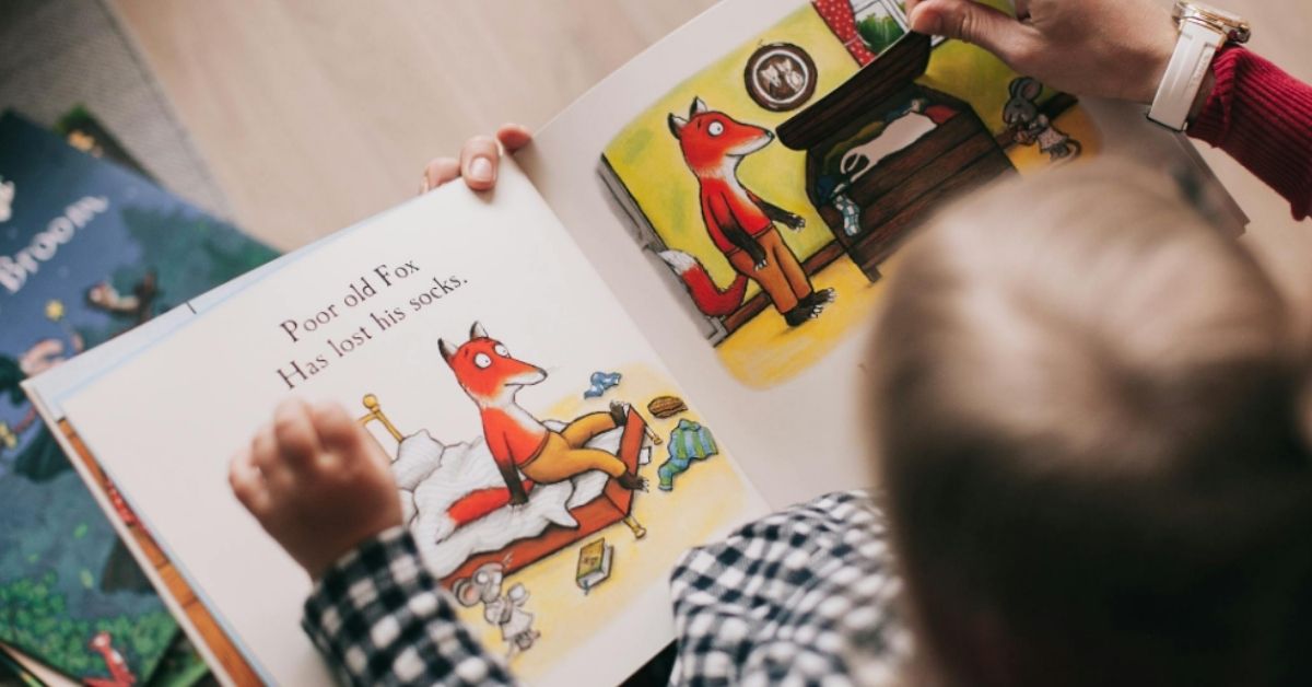 Close-up of a little boy reading a book about a fox losing his socks as he sits in his grandmother's lap