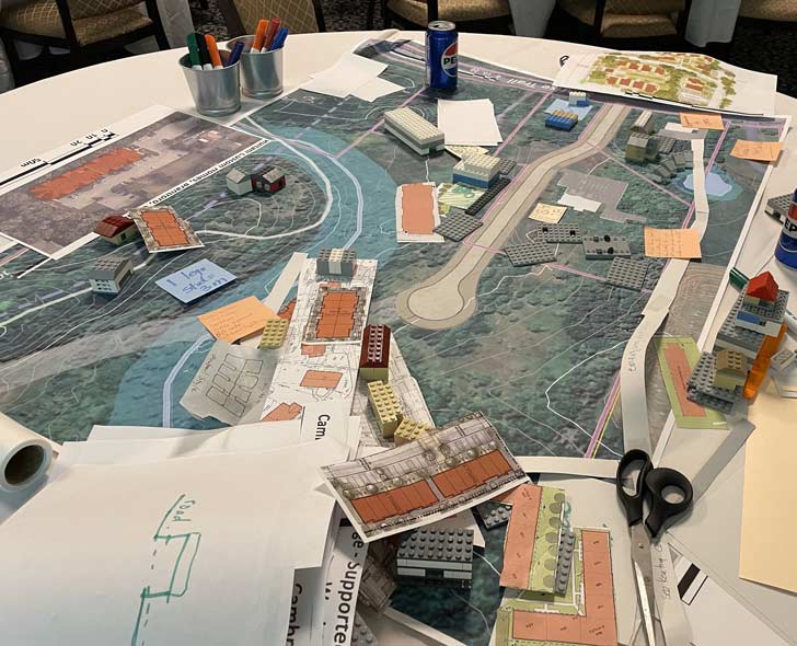 An aerial view of a topographical map, topped with blueprints and lego-builds of future affordable housing developments
