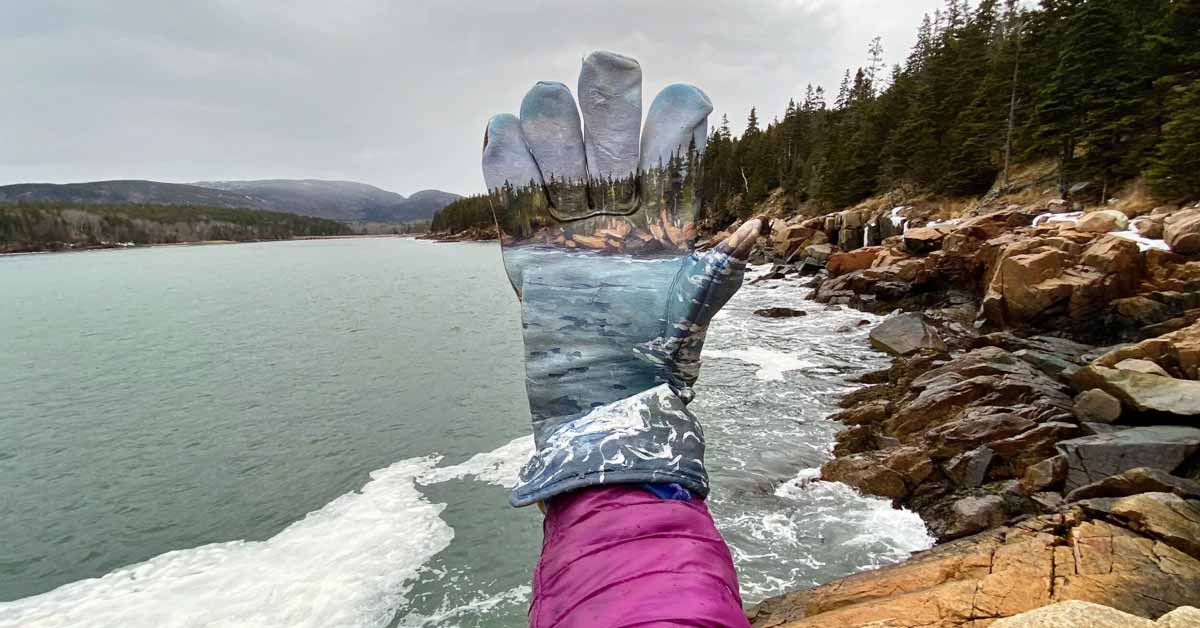 An artwork by Mariah Reading, a landscape painting of Acadia National Park on a discarded glove, called "Lend A Hand"
