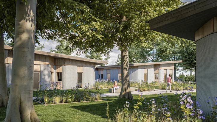 A courtyard of 3D printed student housing in Denmark, surrounded by lush green trees