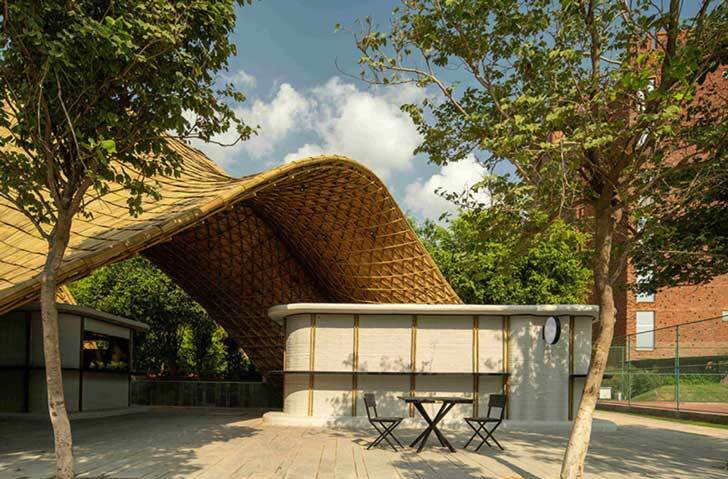 The Hungry Caterpillar -- a bamboo structure winding around kitchen stalls printed from concrete.  This is a shot of one of the kitchen stalls beside a table and two chairs. You can see the blue sky dotted with clouds above the structure