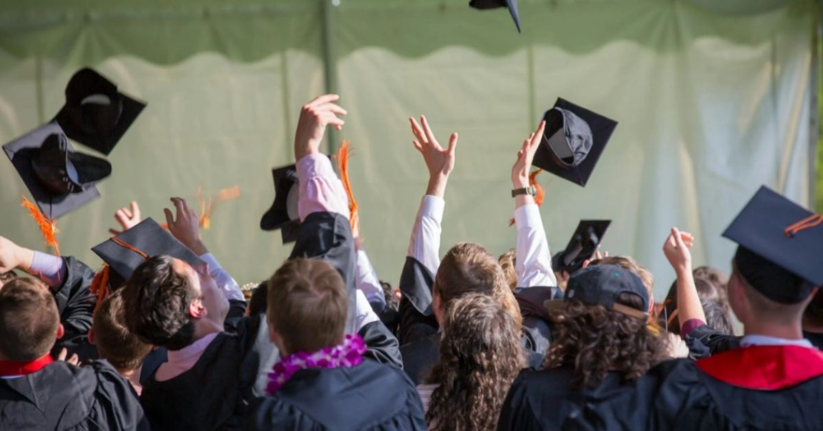 A group of college graduates throw their caps up in the air.