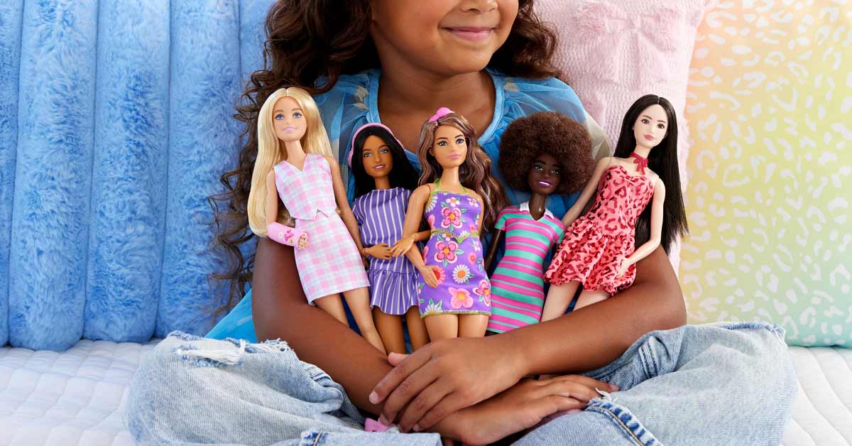 A close-up of a little girl holding a collection of Barbie dolls in her arms