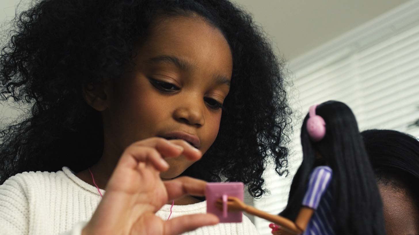 A 5-year-old Black child, Mikko Mirage, plays with an autistic Barbie doll