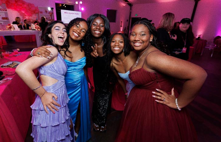 A group of five teen girls smile together at prom