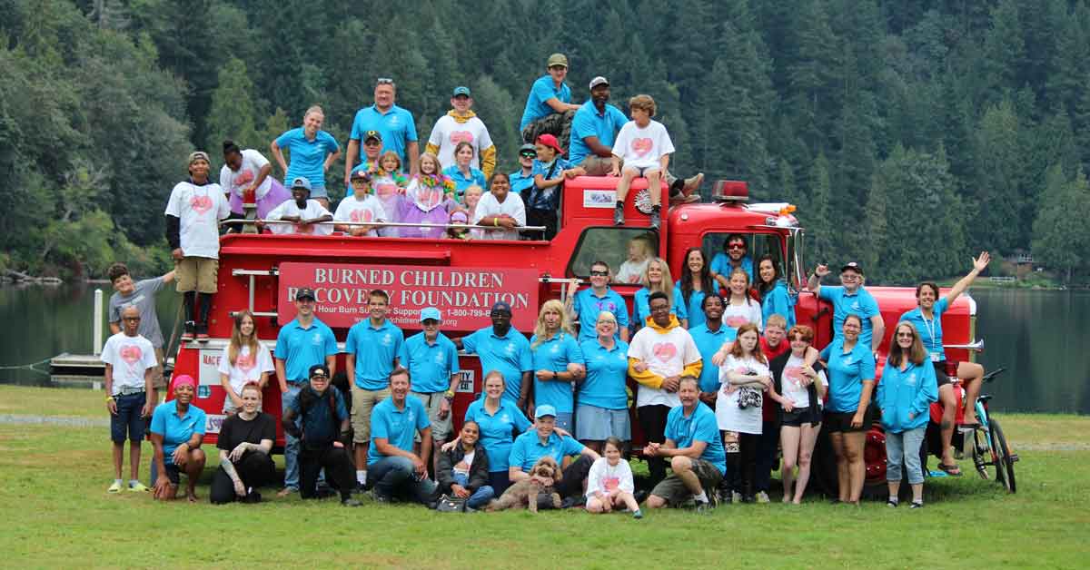 Children and adults from the Burned Children Recovery Foundation pose with a fire truck at a summer camp