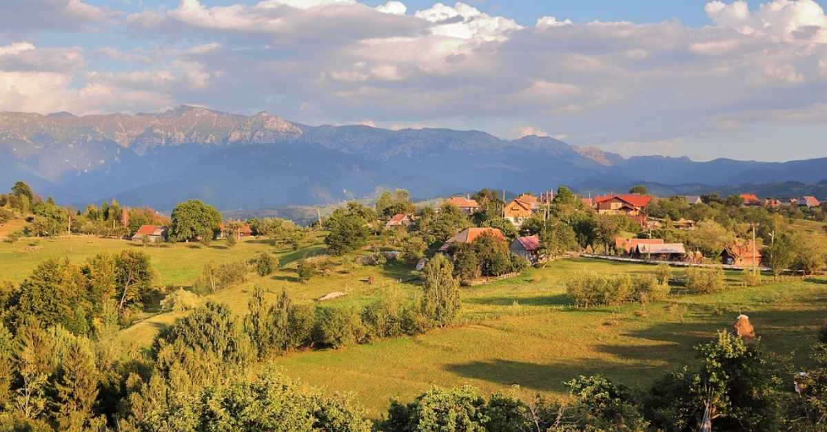 Countryside in Romania: Rolling fields of green with a sky full of clouds behind them. 