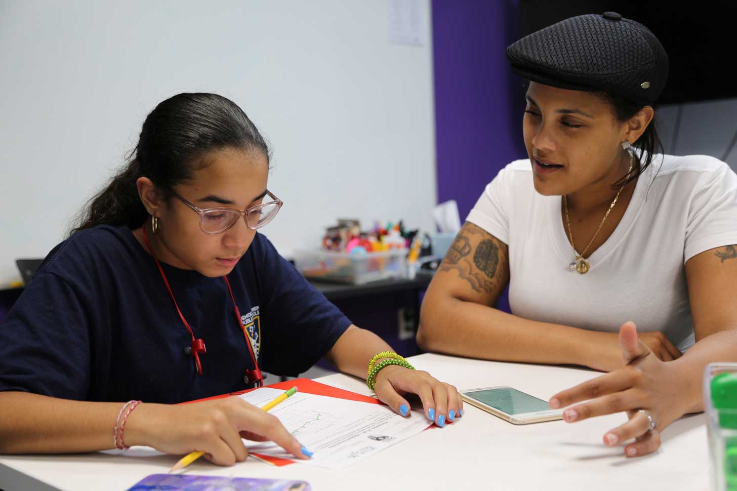 A student sits with a tutor and works on homework