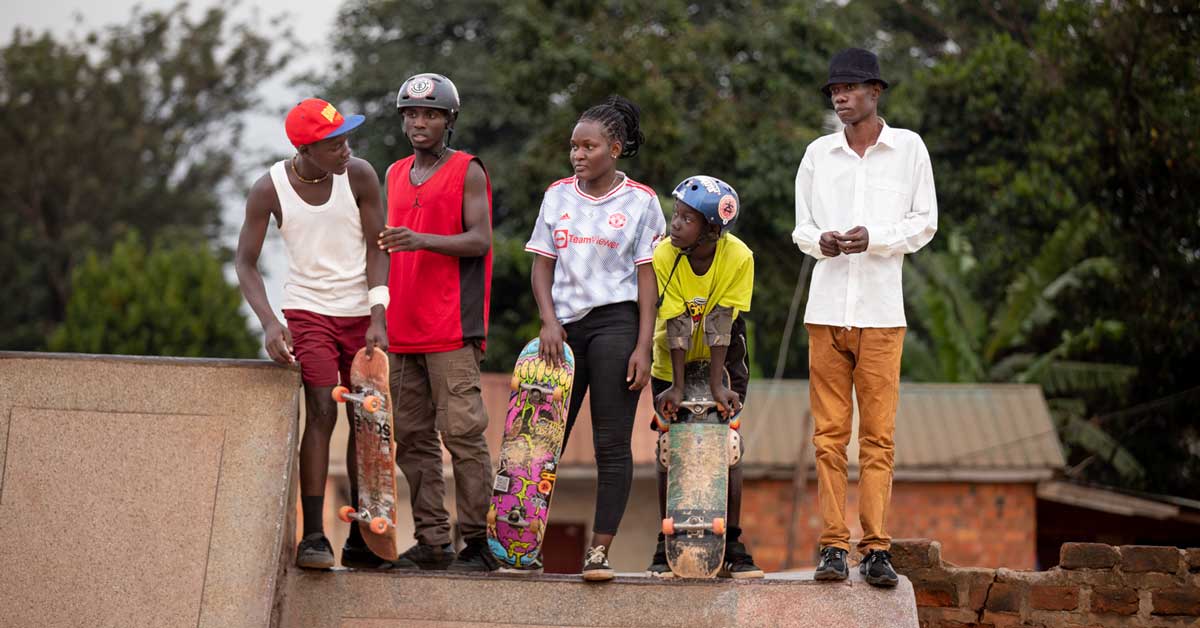 A crew of skateboarders in Uganda wait for their turn on a ramp at a skatepark hosted by Uganda Skateboard Society