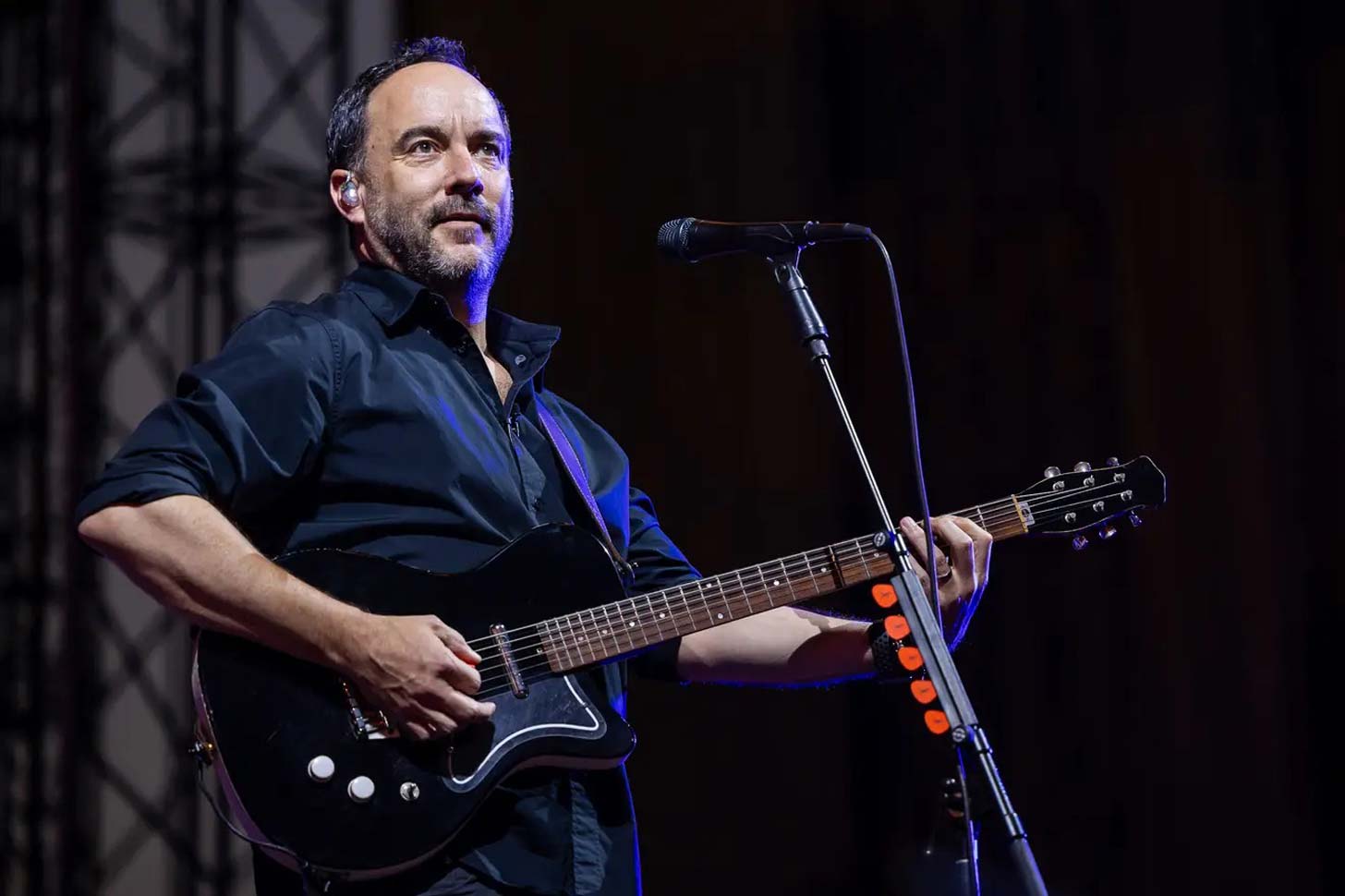 Dave Matthews plays guitar and stands in front of a microphone on stage at The Gorge