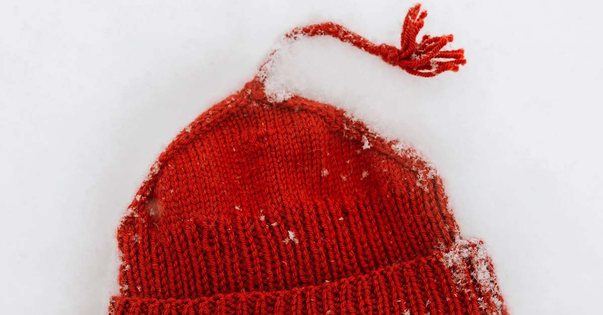 A red knitted "melt the ICE" hat sits in fresh white snow