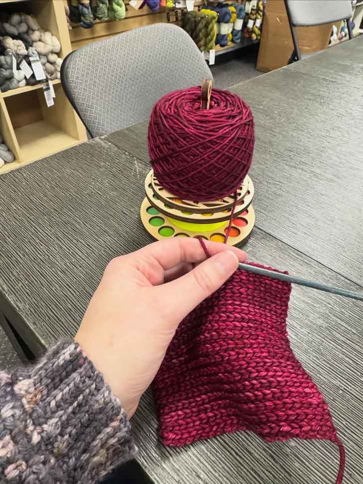 A person crochets a maroon beanie