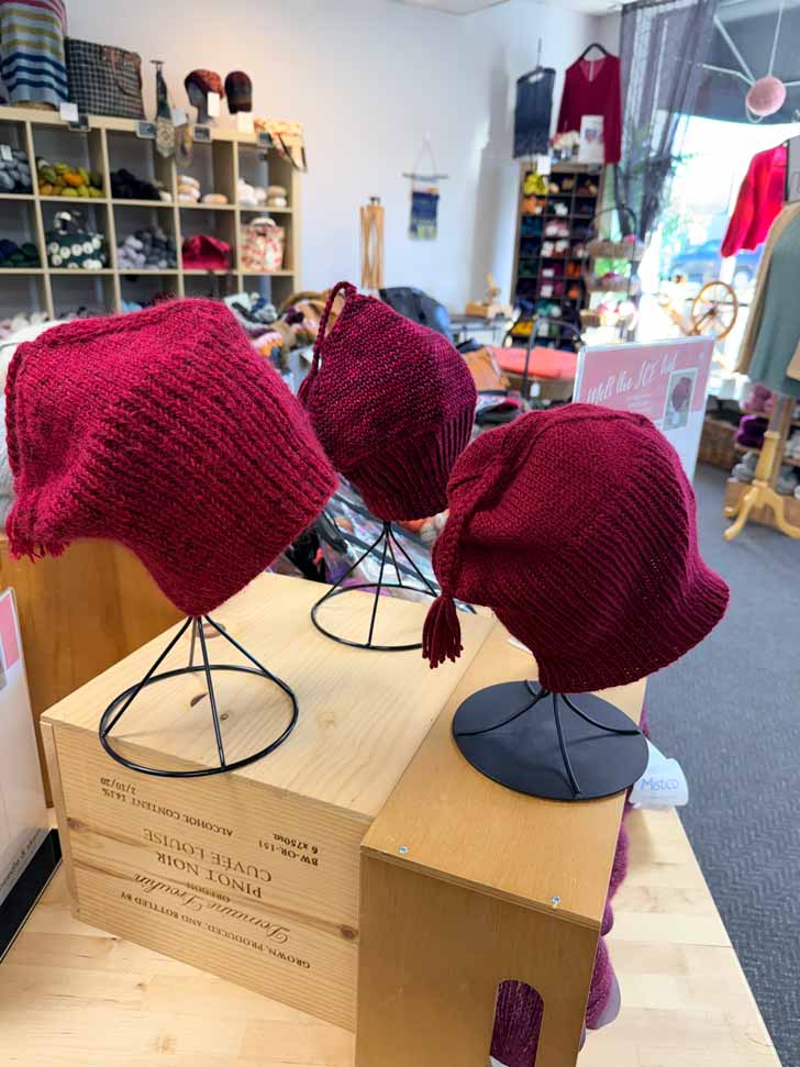 Three red knitted 'Melt the ICE' hats on display in Minnesota yarn shop Needle & Skein