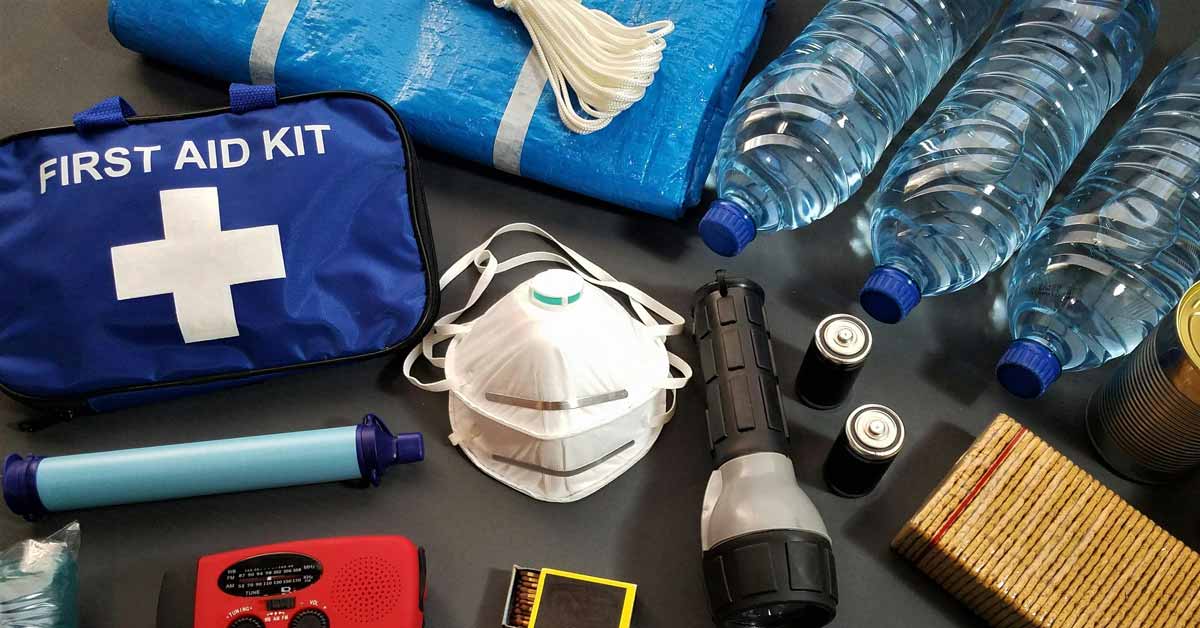 Items in a disaster preparedness kit: A first aid kid, water bottles, a mask, matches, and crackers.