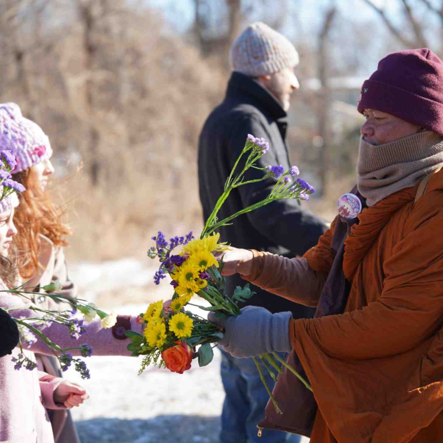 A Buddhist monk exchanges flowers with young girls in a crowd.
