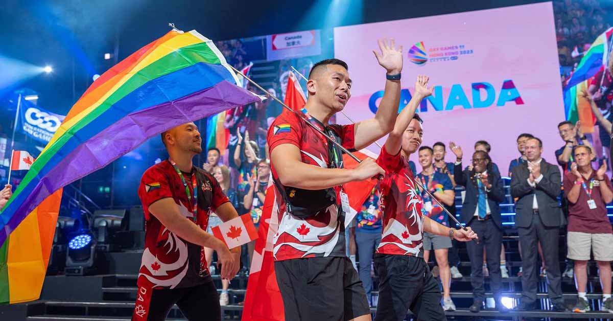 A competitor at the 2022 Gay Games waves while carrying a rainbow Pride flag