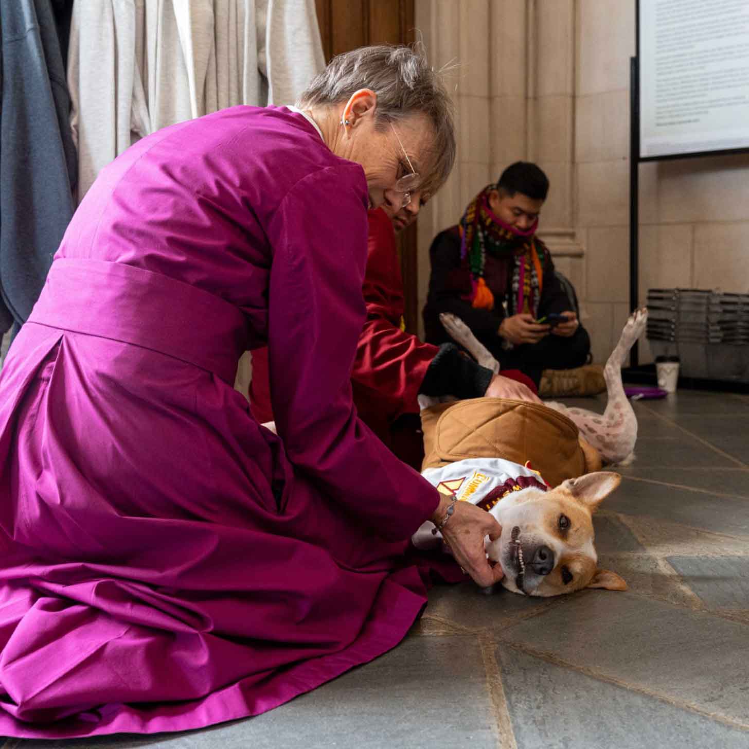 Rev. Marianne Edgar Budde pets a dog inside of a church