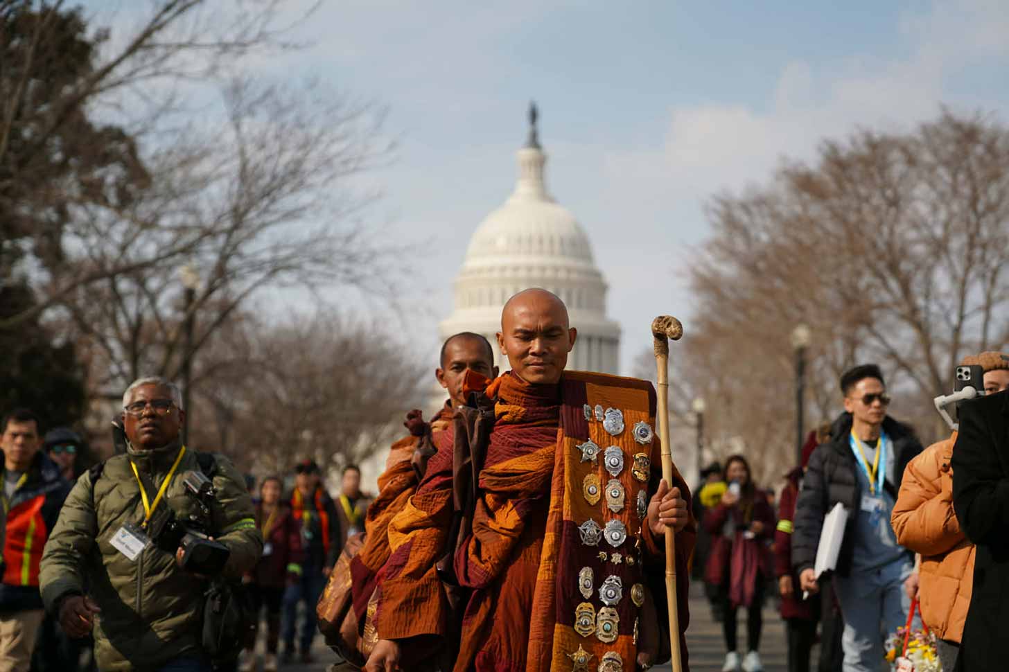 A group of monks in orange robes walk along the National Mall in Washington, D.C.