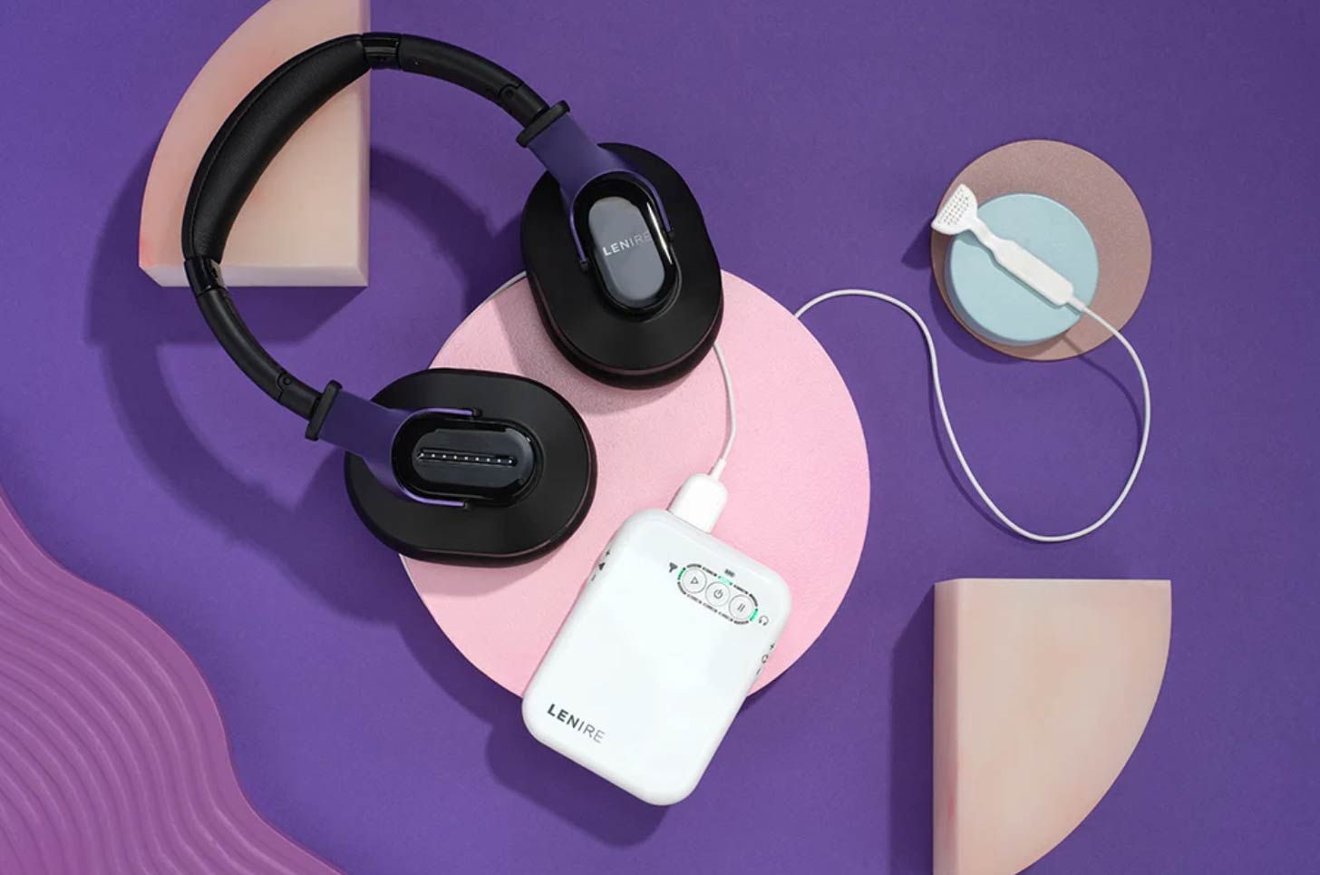 A pair of headphones sits on a purple background next to a Lenire tinnitus device