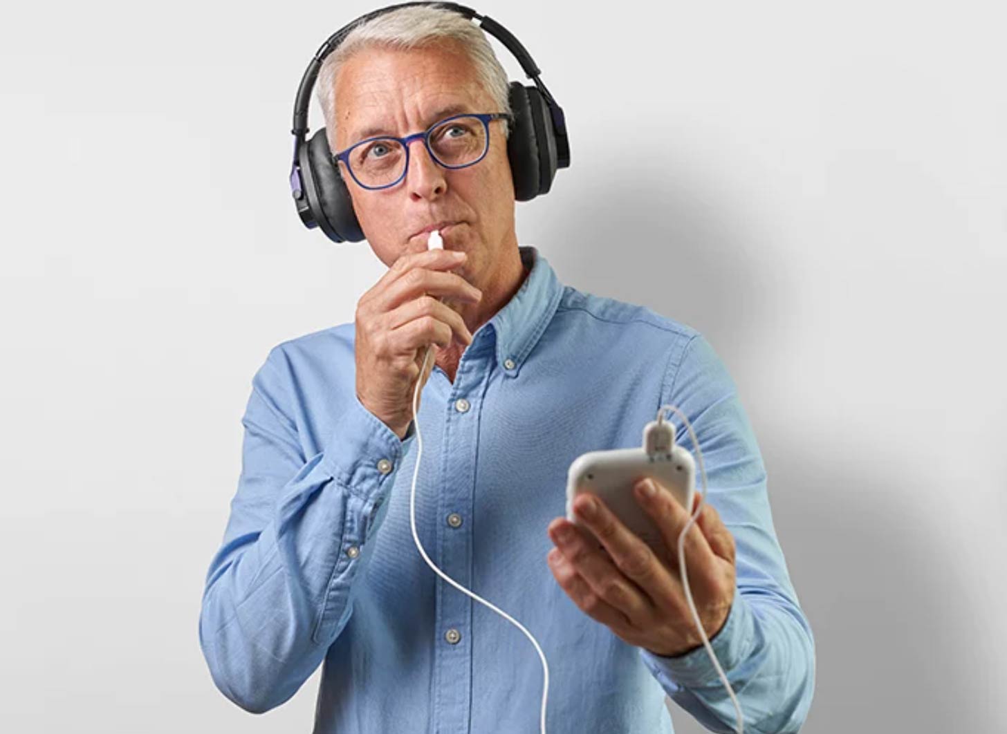 A man wears black headphones over his ears while using a Lenire device in his mouth