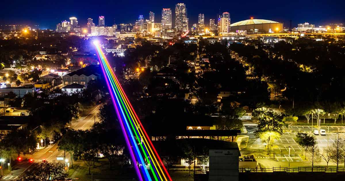An aerial view of downtown St. Petersburg, Florida, with a line of parallel rainbow light beams shining across the sky