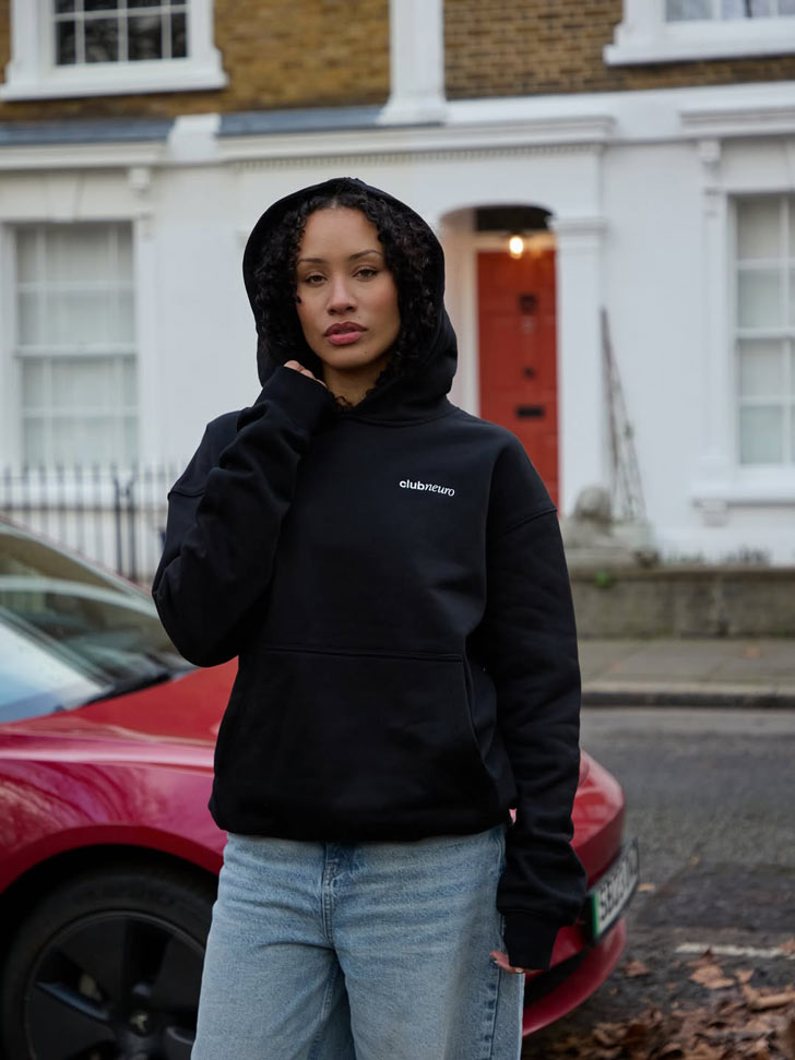 A model wears a black hoodie with the hood up 