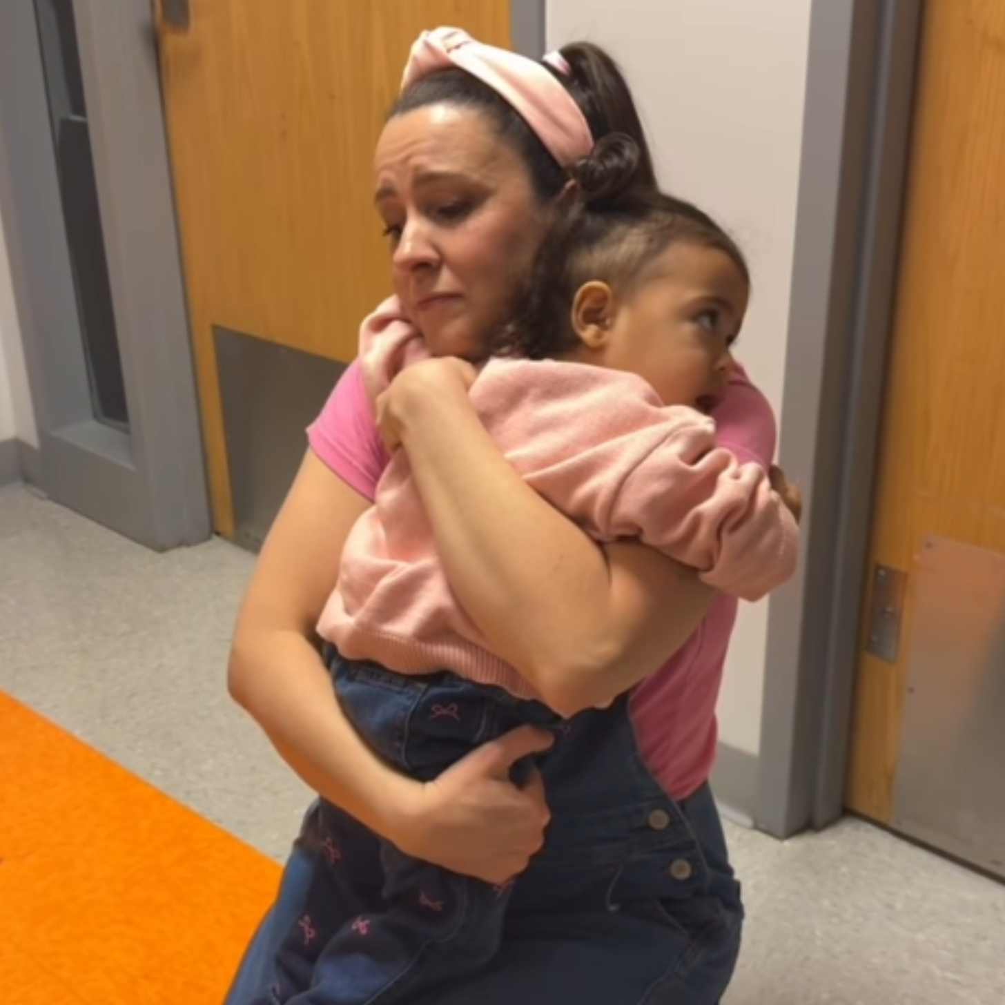 Ms. Rachel holds a toddler close in a classroom setting