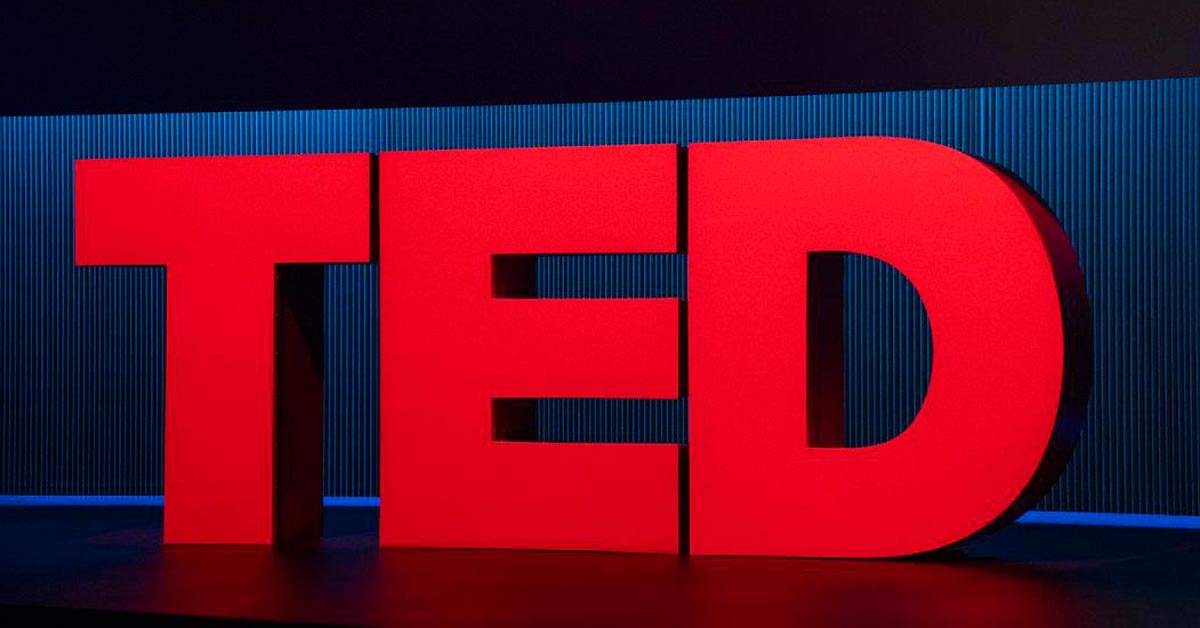Red TED letters on stage in front of a blue curtain