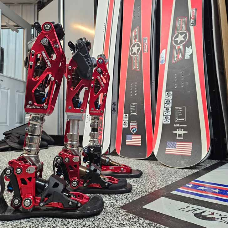 Three prosthetic lower limbs next to three snowboards