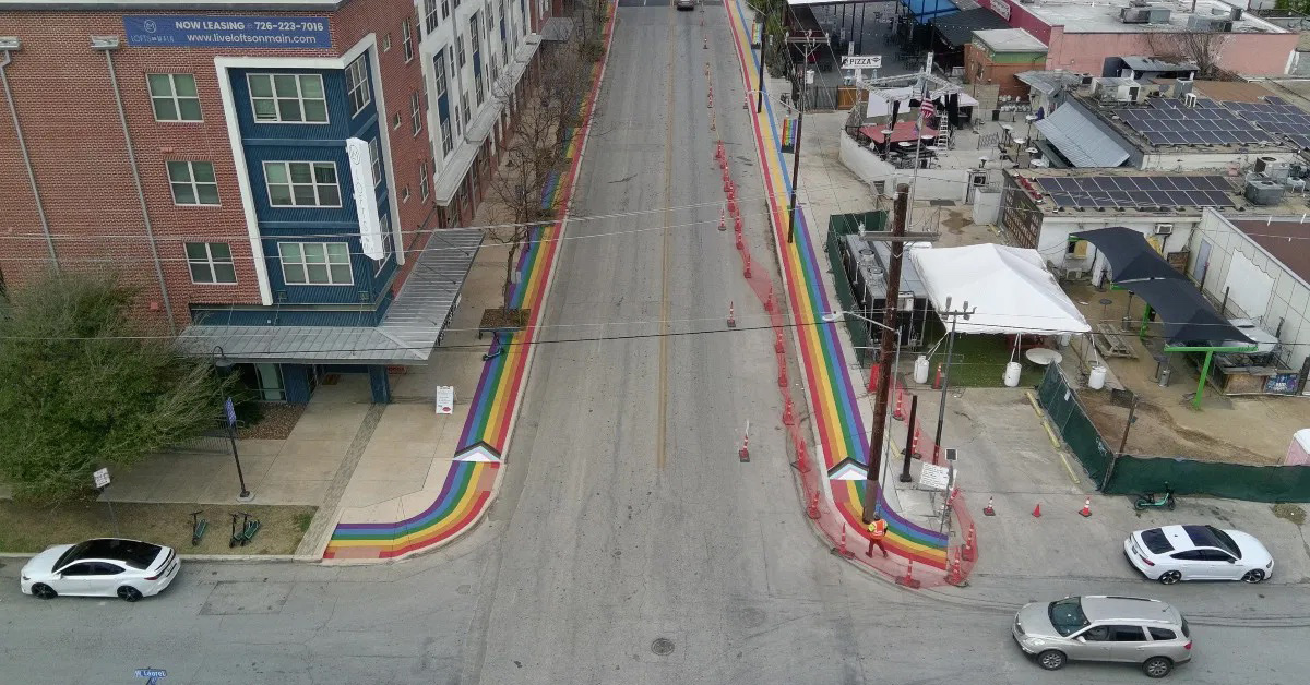 An aerial view of a street in San Antonio, Texas, where the sidewalks are painted with rainbow stripes
