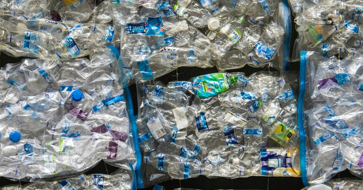 A close-up of a stack of plastic water bottles in a recycling plant