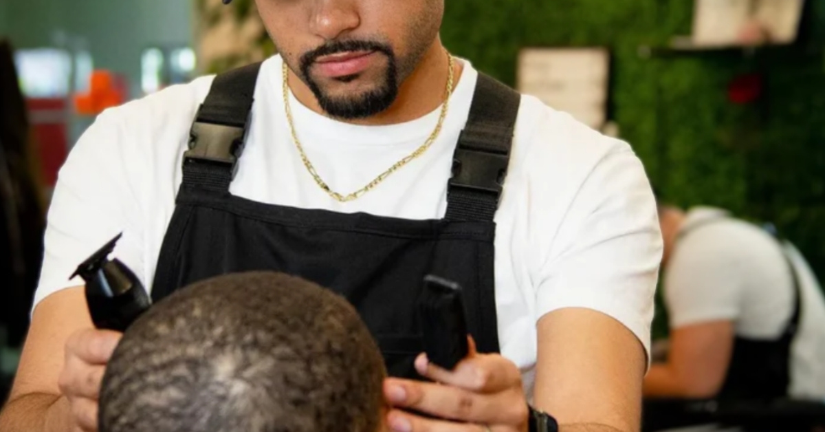 A barber uses two trimmers on the top of a child's head.