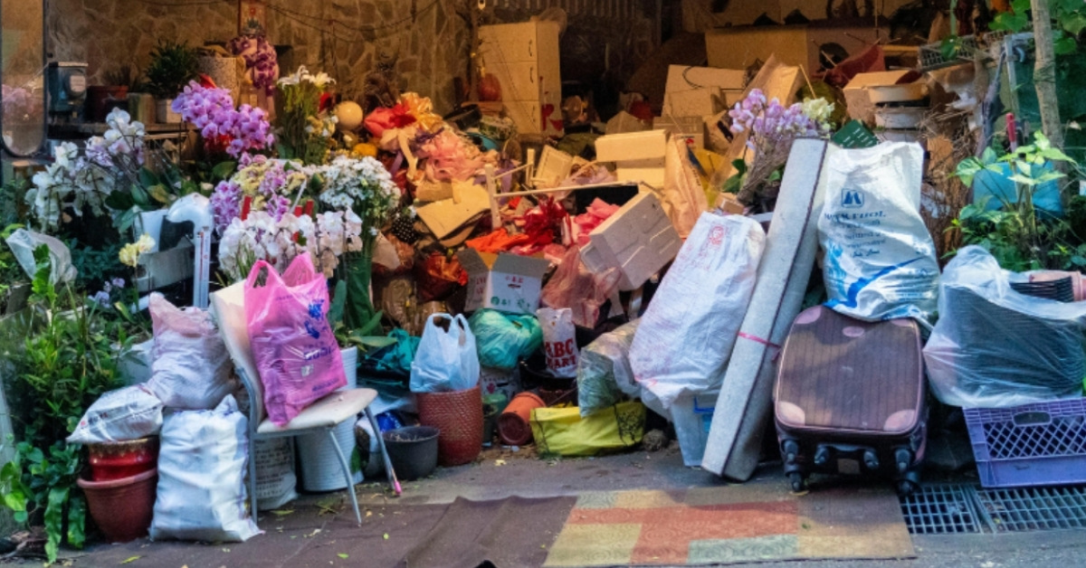 A mixture of trash and clutter outside of a garage on the driveway.