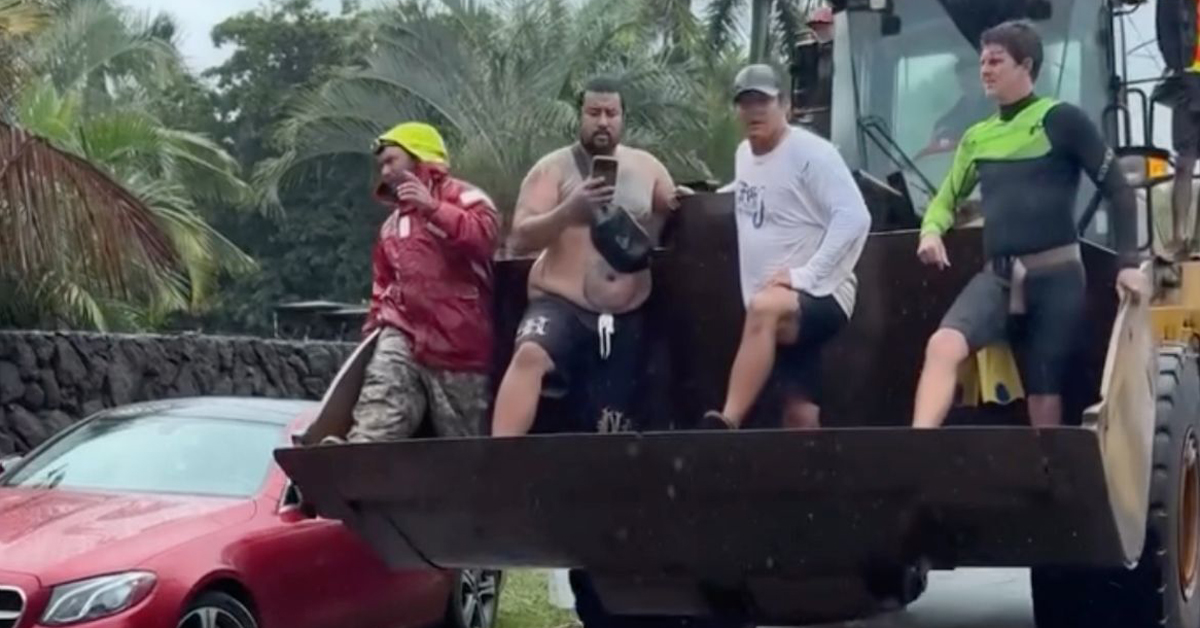 Four men ride in the bucket of a tractor amid catastrophic flooding in Hawaii, on their way to rescue neighbors in need