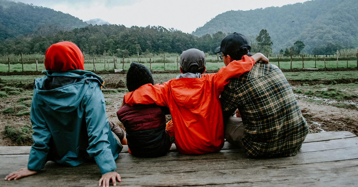 A family sits together looking at a mountain view