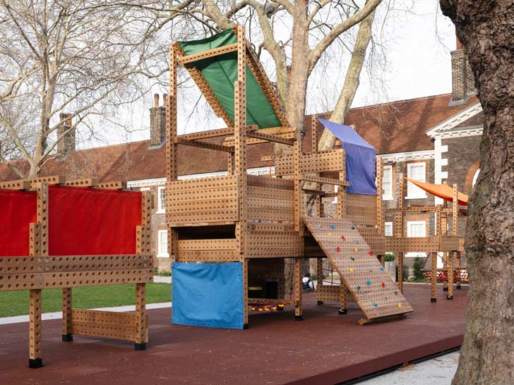 A wooden playground with colorful awnings and holes in the structures